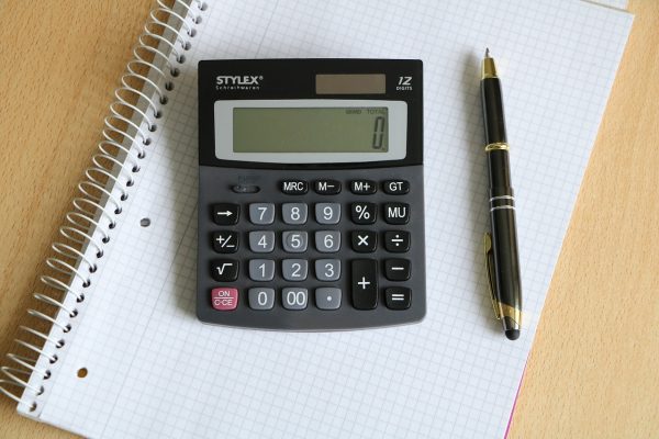 A calculator and pen atop an A4 notebook