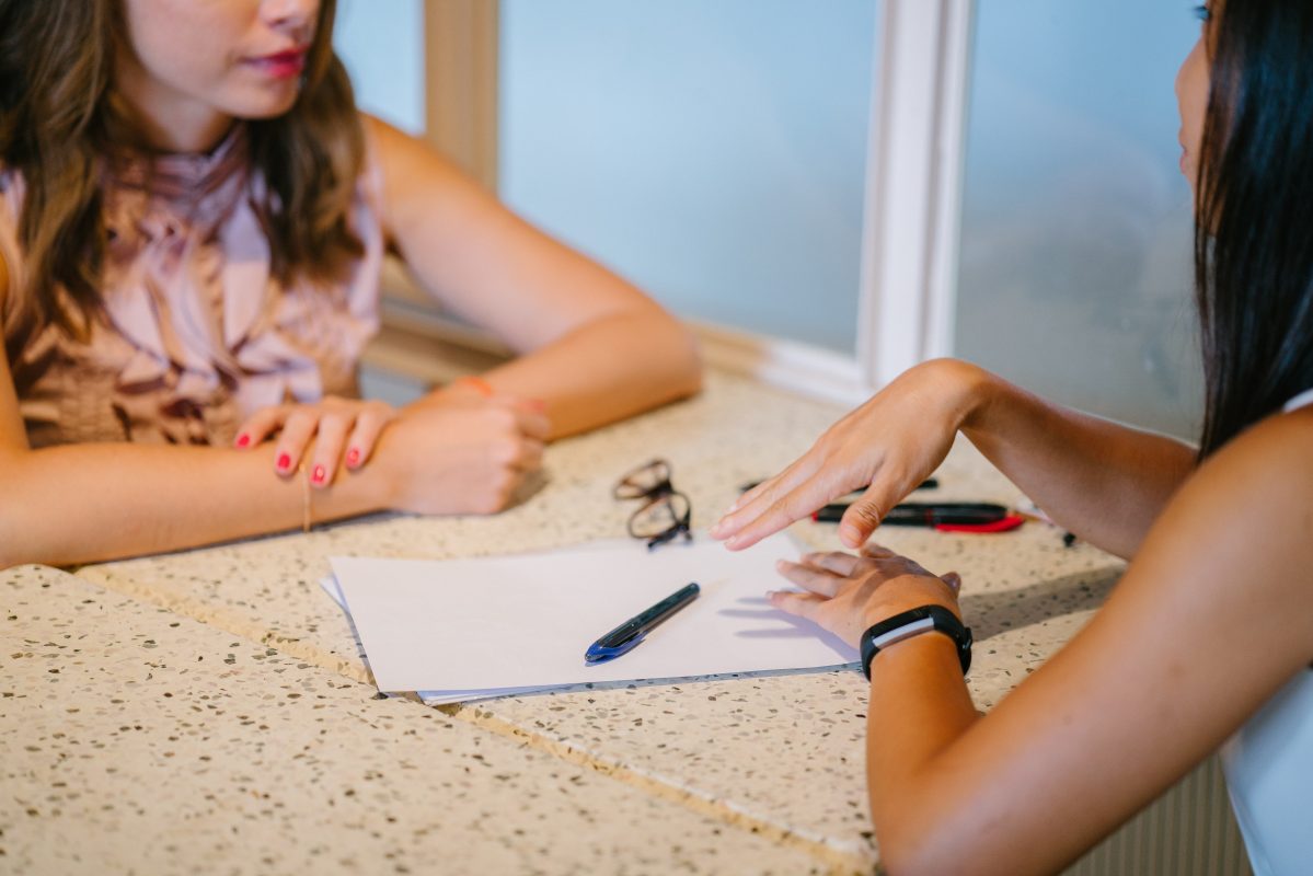 An individual helpfully going over some paperwork with someone else