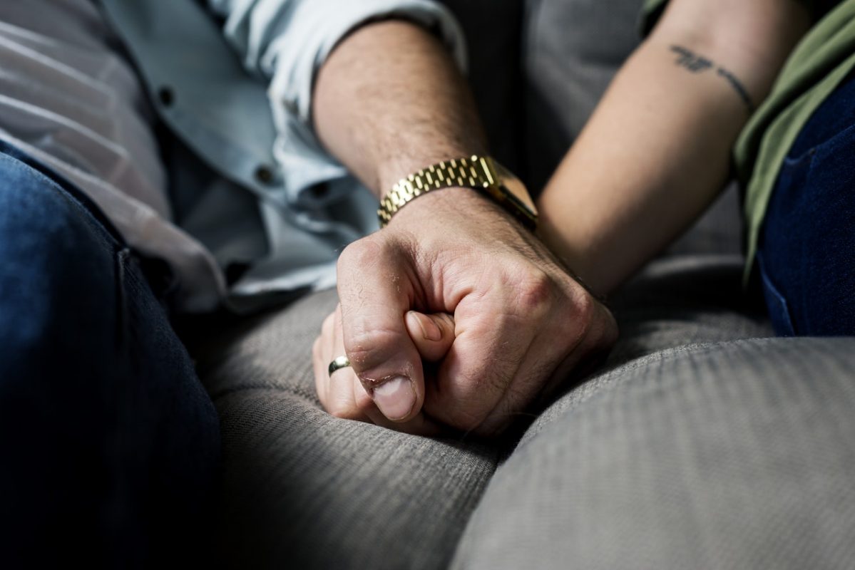 Two people holding hands on a sofa